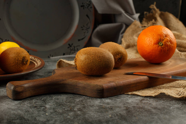 Orange und Kiwies auf einem Holzbrett. - Foto, Bild