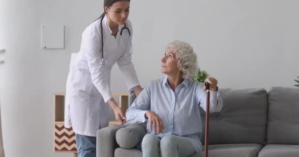 Caring young nurse in uniform helping old disabled hoary woman. - Filmmaterial, Video