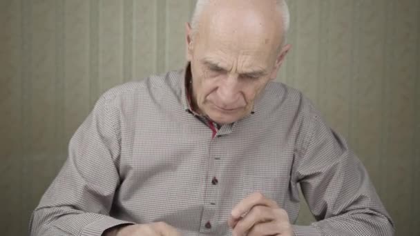 senior citizen in grey shirt takes pill and drinks water - Materiał filmowy, wideo