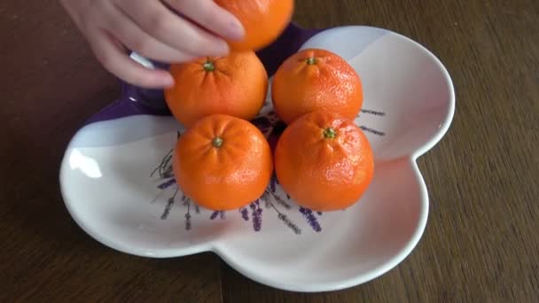 Vruchten in de kom. Baby hand neemt mandarijnen  - Video