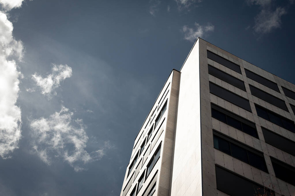 Edifício alto genérico em direção ao céu azul com nuvens
 - Foto, Imagem