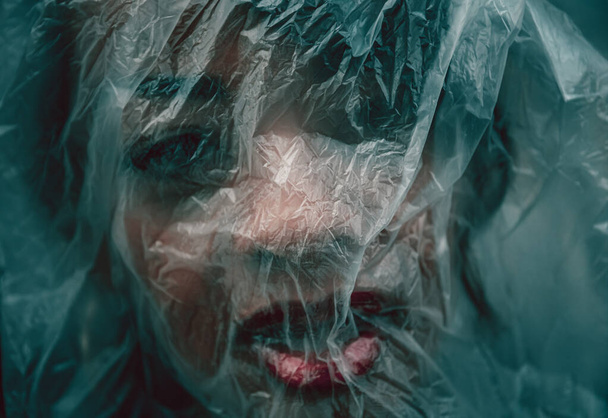 Mujer con la cara cubierta por una lámina de plástico como resultado del virus de la corona o covid-19
 - Foto, imagen