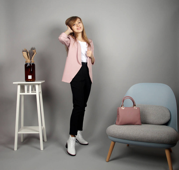 Pretty young blonde european girl at pink coat posing on camera.studio shooting at grey background - Fotografie, Obrázek