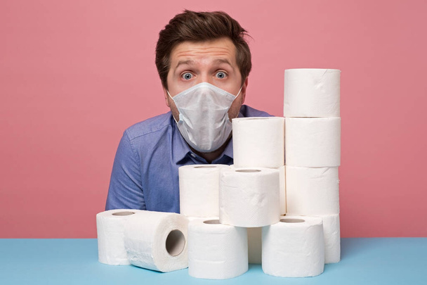 Excited caucasian man in medical mask is happy ge have a stock of toilet paper. Studio shot - Photo, Image