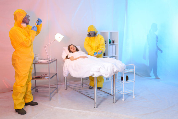 Paramedics wearing protective suits examining patient with virus in quarantine ward - Foto, Bild