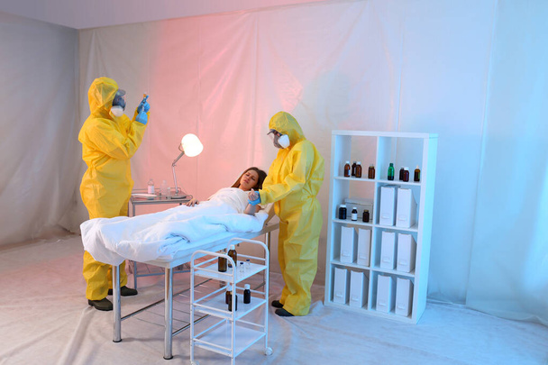 Paramedics wearing protective suits examining patient with virus in quarantine ward - Photo, image