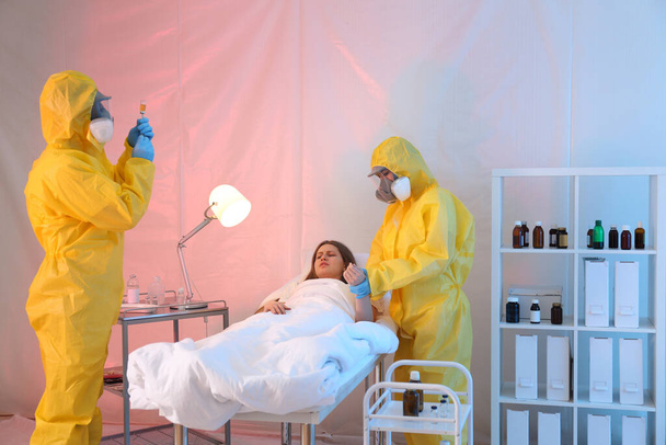 Paramedics wearing protective suits examining patient with virus in quarantine ward - Foto, Bild