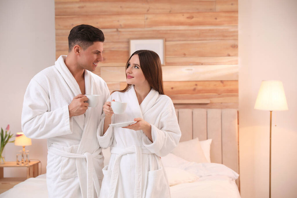Happy couple in bathrobes with coffee in bedroom - Zdjęcie, obraz