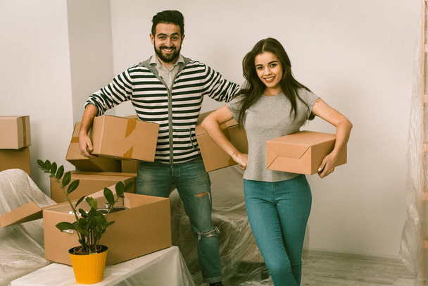 Νεαρό ζευγάρι κινείται σε νέο σπίτι με πολλά κουτιά - Φωτογραφία, εικόνα