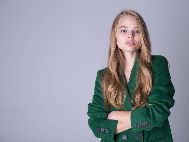 An image of an attractive, elegant blonde standing in a green coat - Фото, изображение