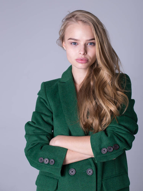 An image of an attractive, elegant blonde standing in a green coat - Foto, imagen