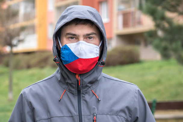Man in face mask with flag of Czech Republic - Coronavirus COVID-19 pandemic concept - Photo, Image