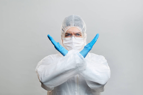 Human in protective suit, medical mask, goggles with arms crossed. Isolated in studio. - Photo, image