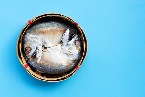 Short mackerel in fish basket on blue background. Top view with copy space - 写真・画像