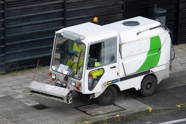 Street cleaning machine working in city. Sweeper cleaning the sidewalk with pressurized water. Maintenance or cleaning concept - Photo, Image