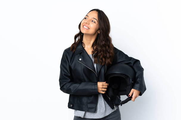 Young woman holding a motorcycle helmet over isolated white background thinking an idea - Photo, image