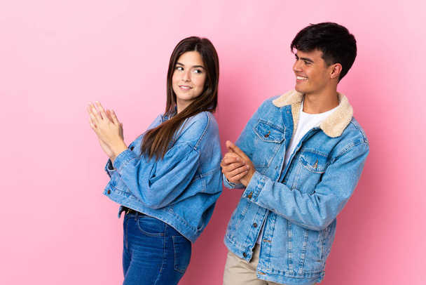 Young couple over isolated pink background applauding after presentation in a conference - Photo, Image