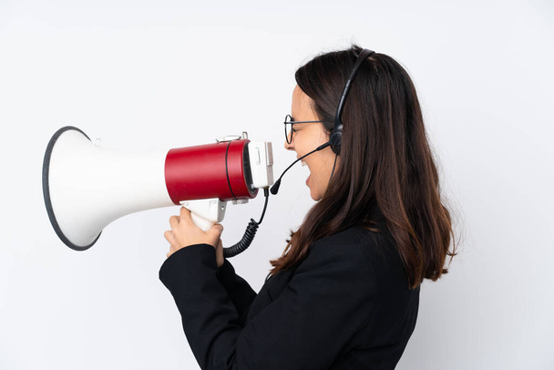 Young telemarketer woman isolated on white background shouting through a megaphone - Zdjęcie, obraz