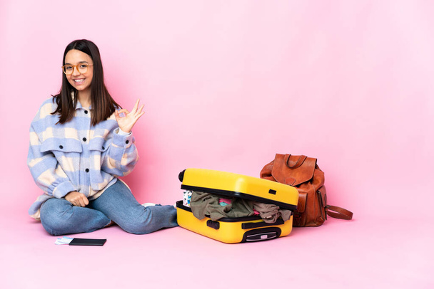 Podróżniczka z walizką siedzącą na podłodze z tabliczką ok palcami - Zdjęcie, obraz