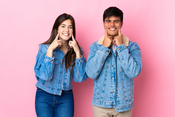 Молода пара над ізольованим рожевим фоном посміхається з щасливим і приємним виразом
 - Фото, зображення