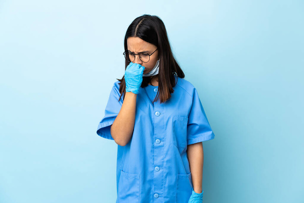 Chirurg Frau über isolierten blauen Hintergrund hat Zweifel - Foto, Bild