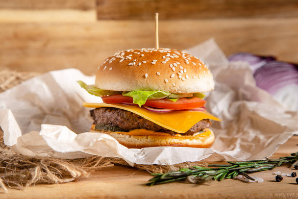 Hamburger with cheese tomatoes and lettuce on sesame seed bun  - Фото, изображение