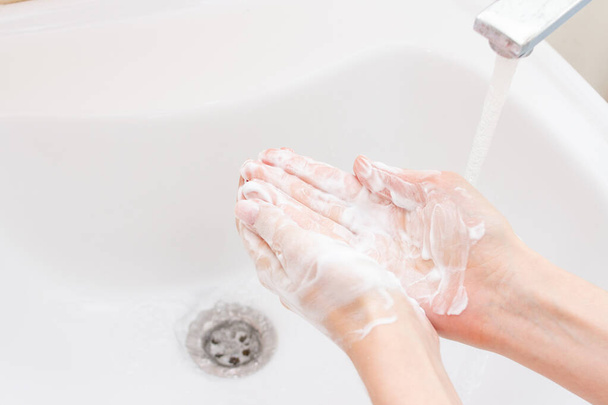 vrouw wassen handen over spoelbak in badkamer - Foto, afbeelding