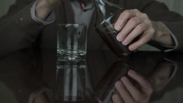 senior man trembling hands pour cognac into glass closeup - Materiał filmowy, wideo