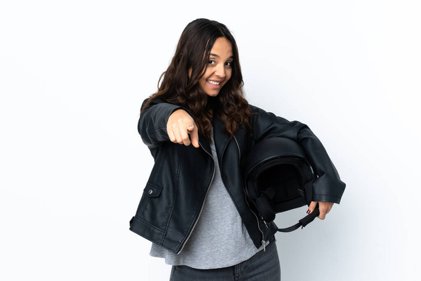 Young woman holding a motorcycle helmet over isolated white background making phone gesture and pointing front - Photo, Image