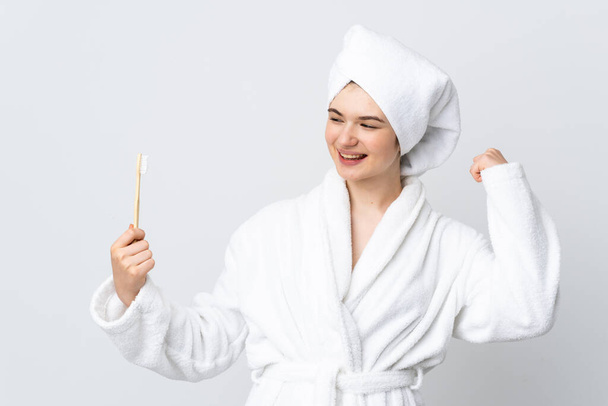 Young woman in a bathrobe holding toothbrush celebrating a victory - Photo, Image