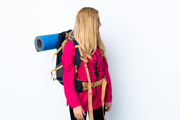 Young mountaineer woman with a big backpack over isolated white background looking to the side - Fotografie, Obrázek