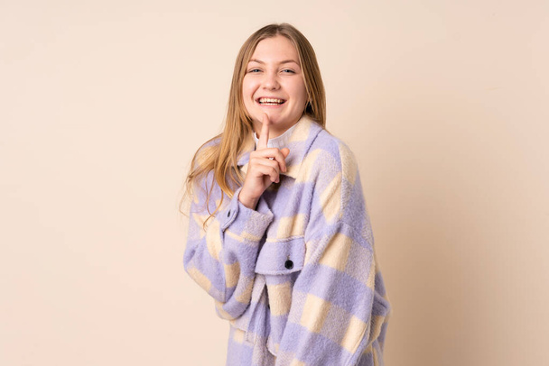 Teenager Ukrainian girl isolated on beige background showing a sign of silence gesture putting finger in mouth - 写真・画像