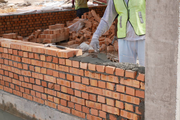 SEREMBAN, MALAYSIA -MARCH 15, 2020: Brickwork by construction workers at the construction site. Workers laying the clay brick and stacked it together using mortar to form the wall.  - Fotó, kép