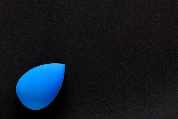Blauwe cosmetische spons op een zwarte achtergrond. Bovenaanzicht - Foto, afbeelding