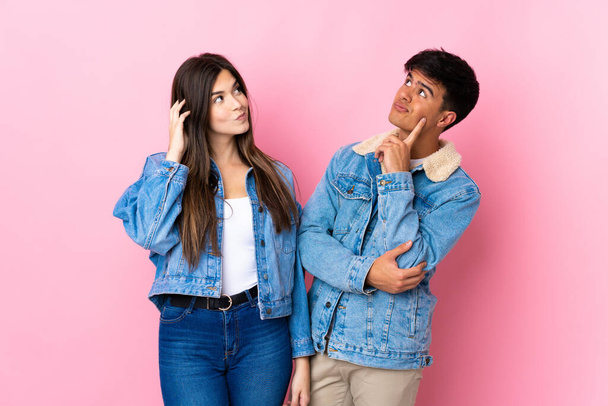 Young couple over isolated pink background thinking an idea while scratching head - Foto, immagini