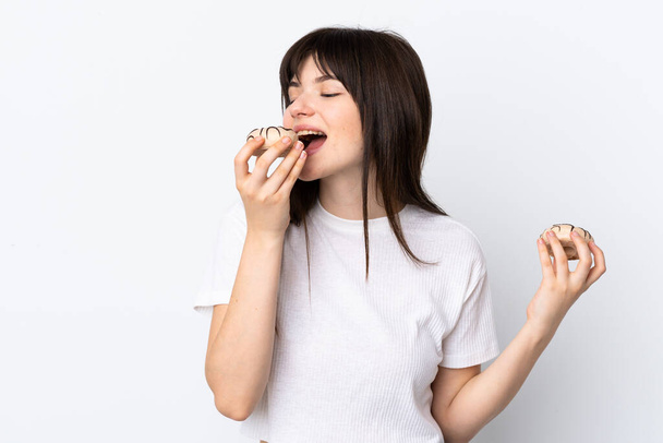 Young Ukrainian woman isolated on white background eating a donut - Foto, afbeelding