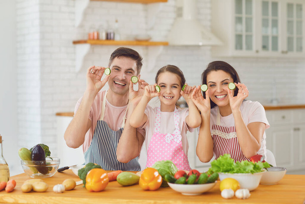 Happy family smiling at a table with fresh vegetables make salad in the kitchen. - Fotografie, Obrázek