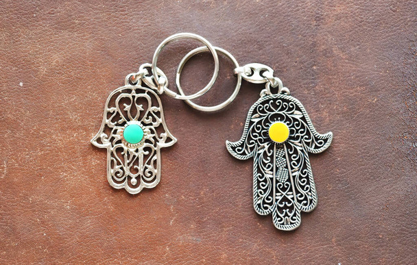Dva kroužky na klíče v podobě Fatima Hand na hnědém koženém pozadí. Starověký symbol a tradiční moderní turistický suvenýr Tuniska - Fotografie, Obrázek