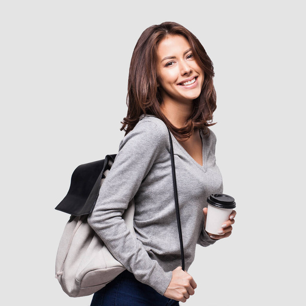 Young beautiful woman with backpack holding coffee  - Фото, изображение