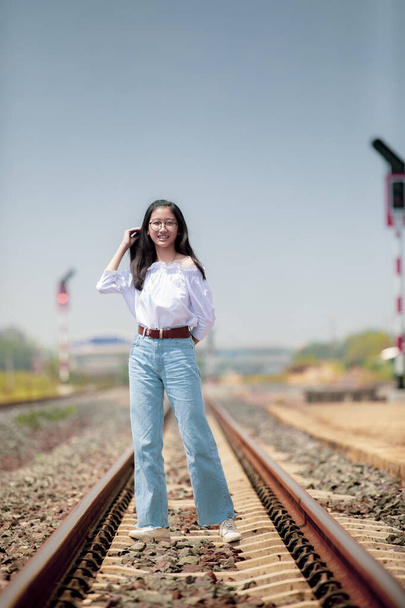 Porträt eines asiatischen Teenagers, der auf Bahngleisen steht - Foto, Bild