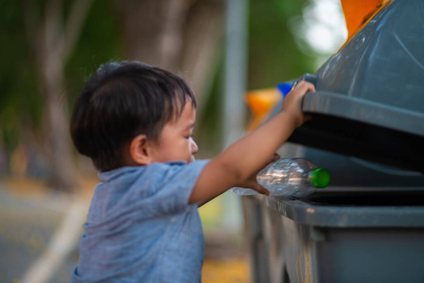 Pequeño niño asiático bebé lanzando botella de plástico en la papelera de reciclaje en el parque público, Eco niño amigable Reciclaje, Salvar el mundo & concepto de medio ambiente. - Foto, Imagen