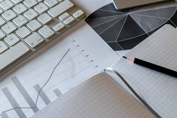 Papírmunka az asztalon. A pénzügyi adatokmányok grafikonokat ábrázolnak az analitikai munkaterületről. Fényvisszaverő fény és fáklya. - Fotó, kép