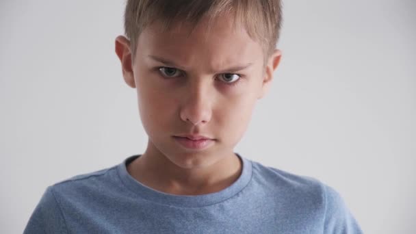 Frowning unhappy young caucasian child looking angry and arms crossed over white background - Footage, Video