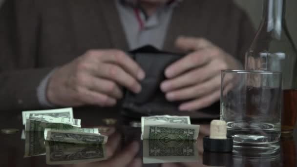 old alcoholic closes wallet and drinks cognac over banknotes - Filmagem, Vídeo