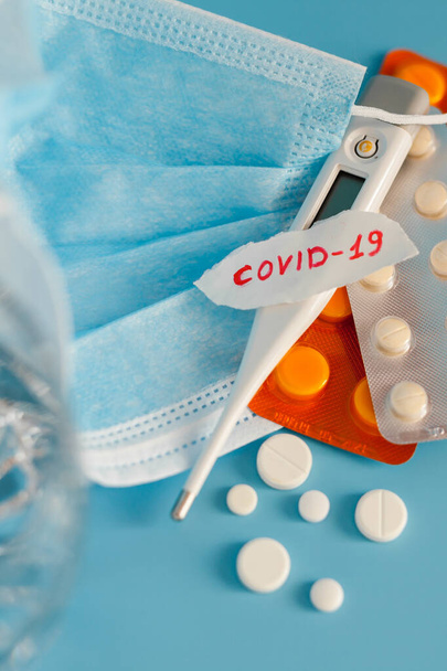 Нове коронавірусне захворювання на ім'я 2019 nCoV почерк на папері з дихальною маскою, термометром та таблетками, селективний акцент на синьому фоні
 - Фото, зображення