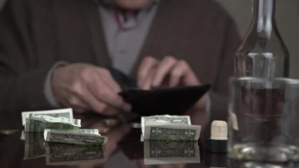 aged alcoholic looks into black leather wallet and drinks - Imágenes, Vídeo