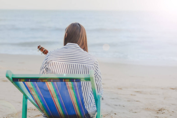 solo músico mujer viaje relajarse y sentarse en la silla de playa ver a la playa y el fondo de la puesta del sol en la temporada de verano
 - Foto, imagen