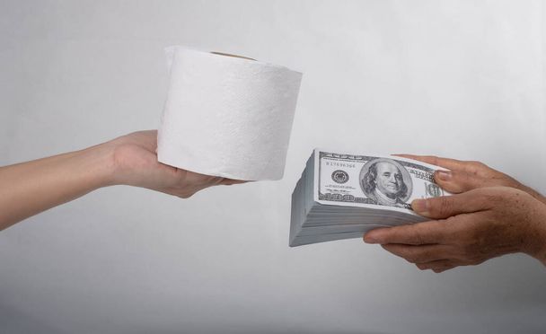 Close up sell buy tissue, hand holds toilet paper tissue and money of 100 US dollars banknote a lot of, That was It costs expensive price and high priced products concept, Doomsday of people pani - Fotó, kép