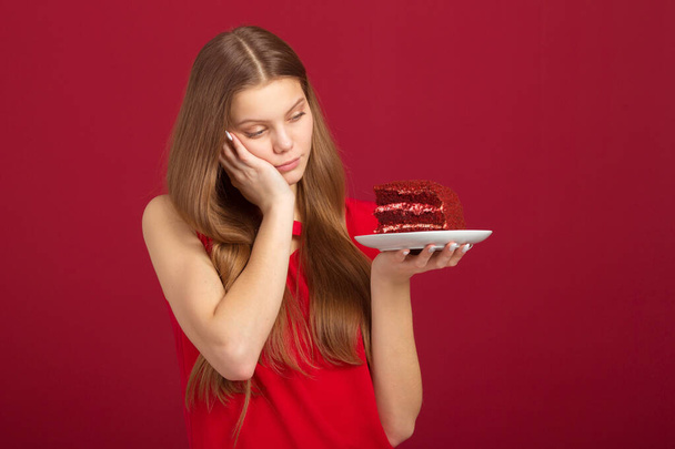 beautiful young woman with her hair on a red background with cake - 写真・画像