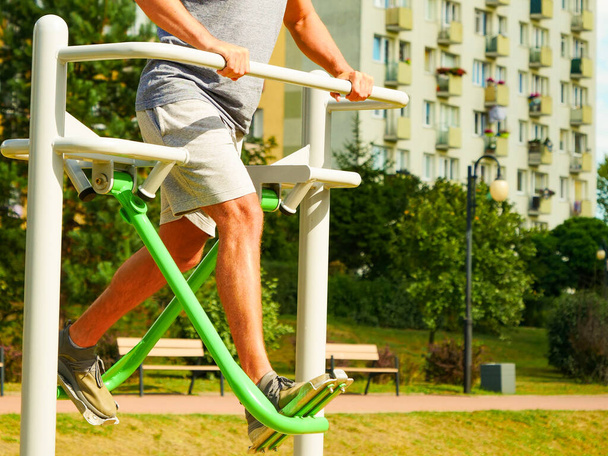 Young man working out in outdoor gym. Sporty guy doing legs exercises on street simulators. Staying fit and healthy. - Φωτογραφία, εικόνα